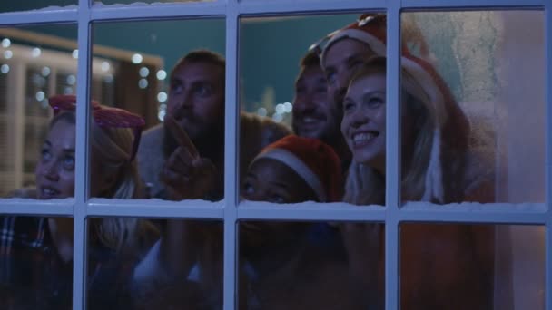 Amigos entusiasmados olhando pela janela durante o Natal — Vídeo de Stock