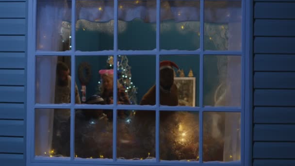 Amigos emocionados mirando por la ventana durante la Navidad — Vídeos de Stock