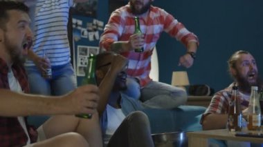 Çok ırklı erkek ve kadın eğleniyor ve spor takımının zaferini kutluyor zaman bira şişeleri ile sorun