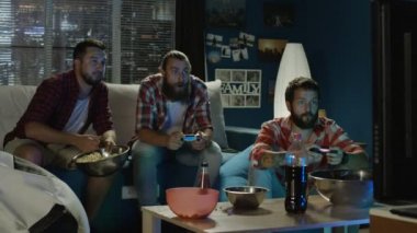 Evde kanepede eğleniyor ve duygusal akşam zevk gamepad ile video oyunu oynarken yetişkin erkek grup