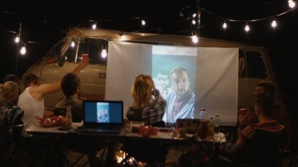 Freunde sehen Film auf dem Bildschirm auf dem Campingplatz — Stockvideo