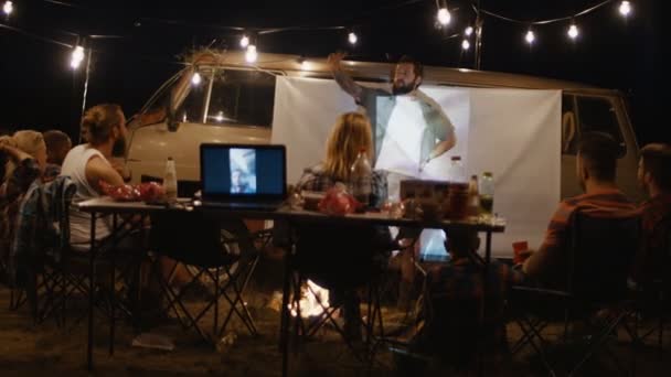 Freunde sehen Film auf dem Bildschirm auf dem Campingplatz — Stockvideo