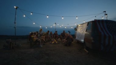 Alacakaranlıkta kamp ateşi üzerinde Sosis kızartma arkadaşlar