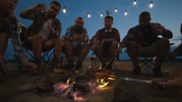 Group of traveling friends frying sausages in campsite — Stock Video