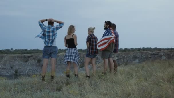 Путешествующие друзья с флагом на скале — стоковое видео