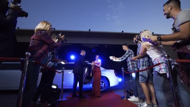 穿着红色礼服的名人女士走出豪华轿车 给她签名 并在红地毯上与粉丝合影 — 图库视频影像