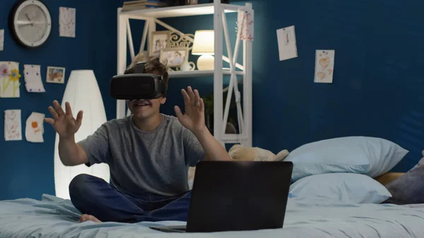 Niño usando gafas VR y portátil en la cama — Foto de Stock