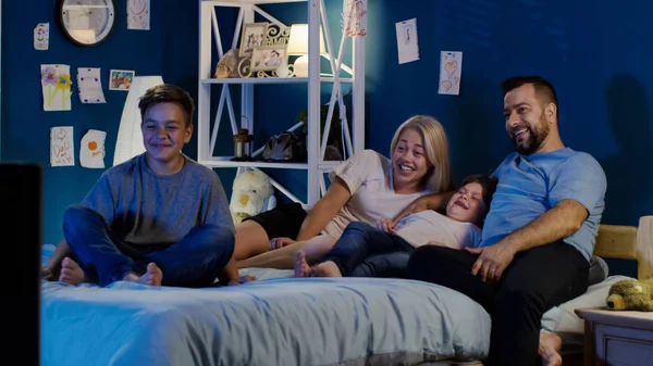 Skrattande familj njuter av Tv på natten — Stockfoto