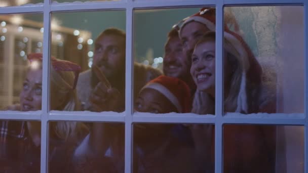 Amigos emocionados mirando por la ventana durante la Navidad — Vídeo de stock