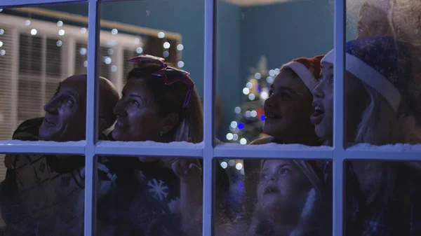 Familia feliz viendo fuegos artificiales a través de la ventana — Foto de Stock