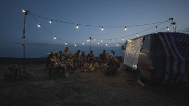 Alacakaranlıkta kamp ateşi üzerinde Sosis kızartma arkadaşlar