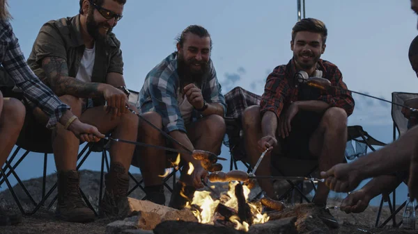 Amis faire frire des saucisses sur le feu de camp au crépuscule — Photo