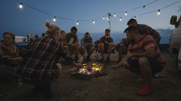 Amis faire frire des saucisses sur le feu de camp au crépuscule — Photo