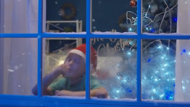 View Frozen Window Little Sleepy Boy Santa Hat Looking Away — Stock Video