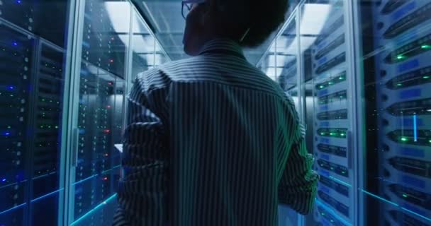 Ingénieur féminin ethnique avec tablette diagnostiquant le matériel du serveur 