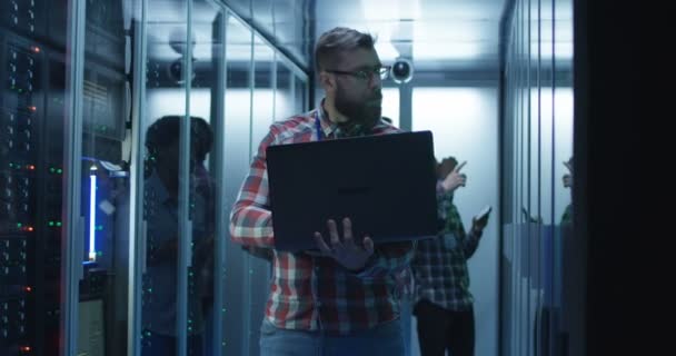 Ingeniero de TI barbudo usando computadora portátil en la sala de servidores — Vídeos de Stock