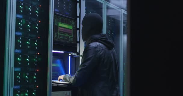 Чёрный человек взламывает компьютерную систему в серверной — стоковое видео
