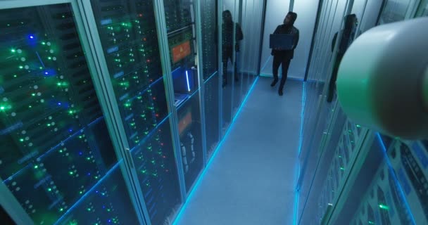 Hacker con portátil en la sala de servidores — Vídeos de Stock