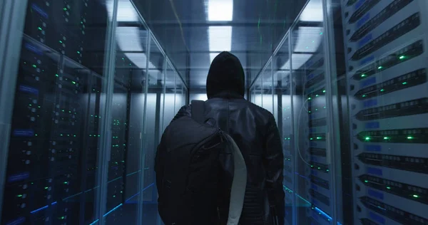 Хакер з рюкзаком, що йде рядами стійкових серверів — стокове фото