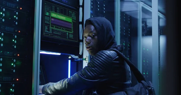 Black man hacking computer system in server room