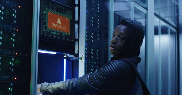 Black man hacking computer system in server room