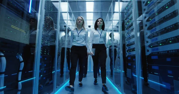 Trabajadores en un centro de datos caminando entre filas de bastidores de servidores — Foto de Stock