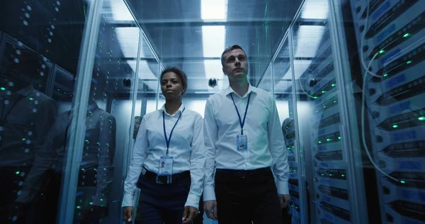 Arbetstagare i ett datacenter som går mellan rader av serverrack — Stockfoto