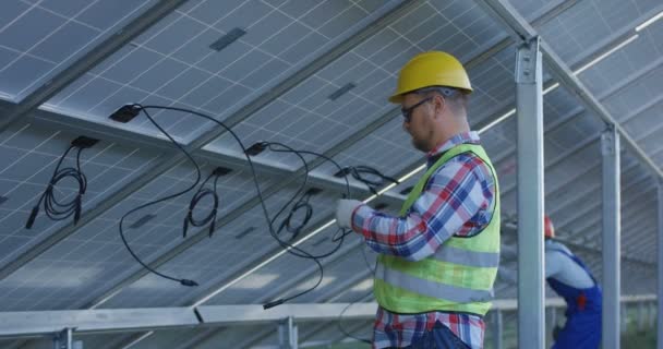 Travailleurs connectant des fils de panneaux solaires — Video