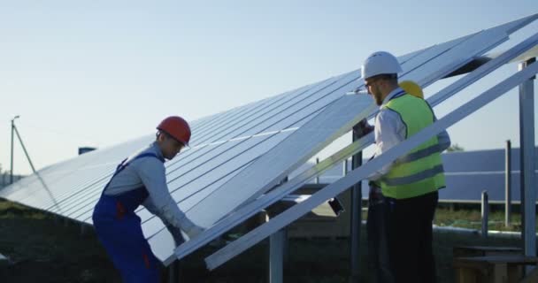 Tres trabajadores instalan un panel solar — Vídeos de Stock