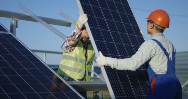 Двоє працівників встановлюють сонячну панель — стокове відео