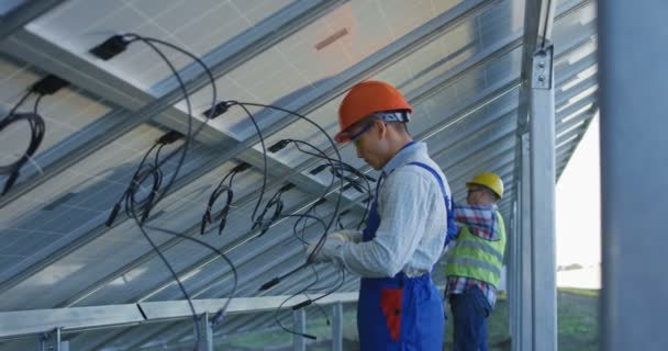 Trabajadores que conectan cables de paneles solares — Vídeos de Stock