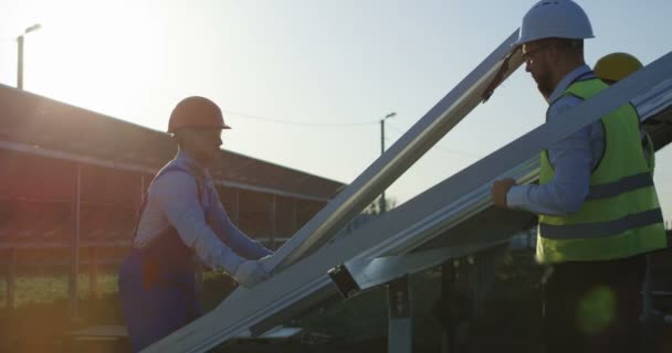 Трое рабочих устанавливают солнечную панель — стоковое видео