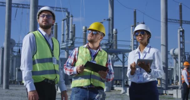 Drie elektrische werknemers reviseren, documenten op een Tablet PC — Stockvideo