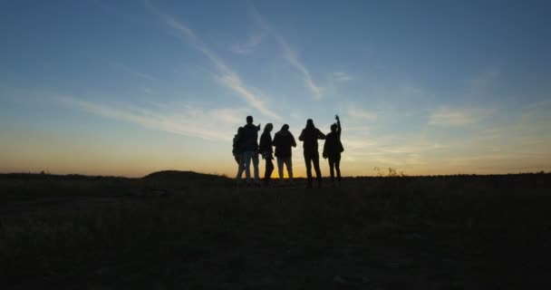 Група охолоджуючих друзів в природі в сутінках — стокове відео