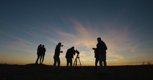 Amigos mirando juntos usando un telescopio profesional — Vídeo de stock