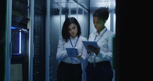 Duas mulheres estão trabalhando em um data center com linhas de racks de servidores — Vídeo de Stock