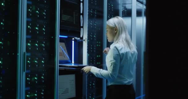 Técnico femenino trabaja en un ordenador portátil en un centro de datos — Vídeo de stock