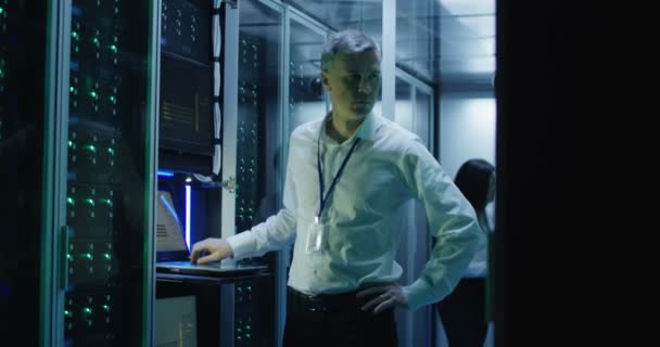 Técnicos trabajan en un ordenador portátil en un centro de datos — Vídeo de stock