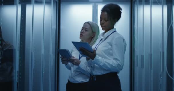 Dwie kobiety pracują w centrum danych z wierszy szaf serwerowych — Wideo stockowe