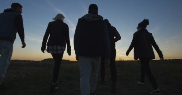 Amigos caminando juntos en el sol poniente — Vídeos de Stock