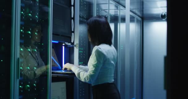 Θηλυκό τεχνικός λειτουργεί σε ένα φορητό υπολογιστή σε ένα κέντρο δεδομένων — Αρχείο Βίντεο