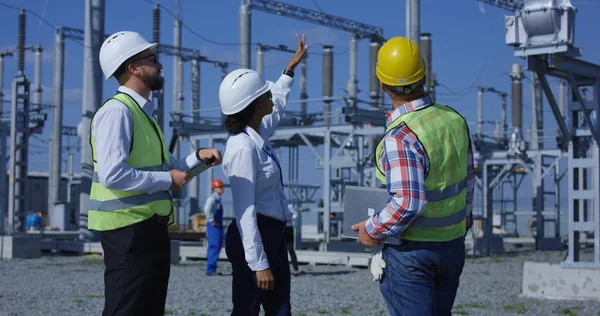 Três trabalhadores elétricos revisando documentos em um tablet — Fotografia de Stock