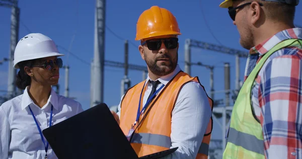 Tre elektriska arbetstagare granska dokument utanför — Stockfoto