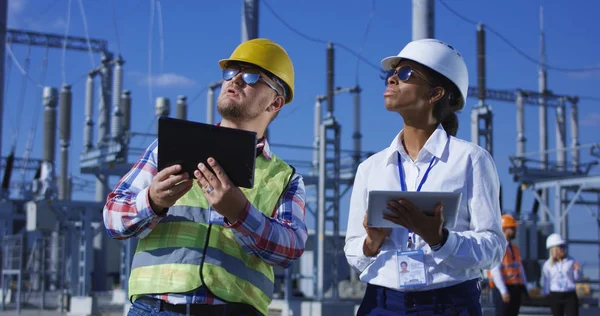 Twee elektrische werknemers op tabletten buiten — Stockfoto