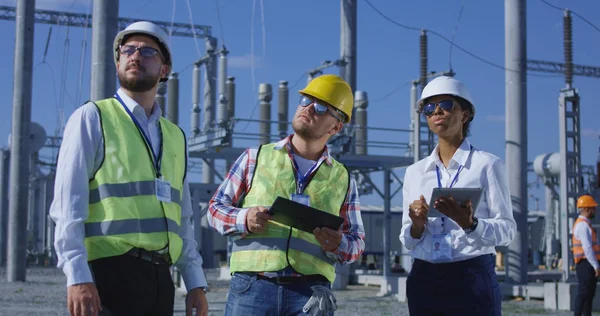 Três trabalhadores elétricos revisando documentos em um tablet — Fotografia de Stock