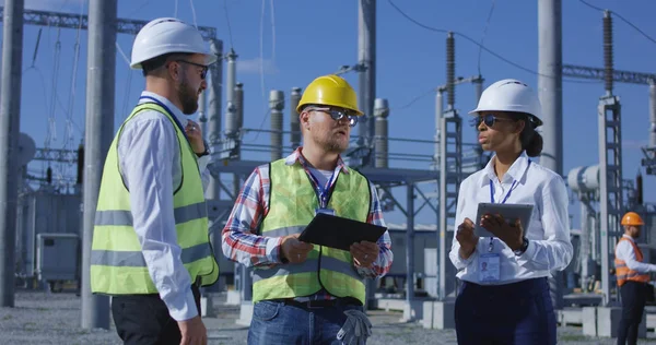 Trois ouvriers en électricité examinant des documents sur une tablette — Photo