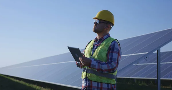 Adult engineer using tablet working among solar panels — Stock Photo, Image