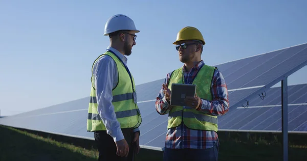 Dos trabajadores eléctricos revisando documentos en una tableta —  Fotos de Stock