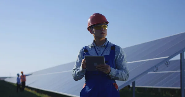 Travailleur ethnique en hardhat utilisant la tablette parmi les panneaux solaires — Photo