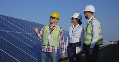 Electrical workers walking at a solar farm clipart
